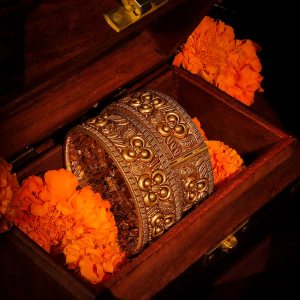Decorative gold bracelet in a wooden box with orange flowers