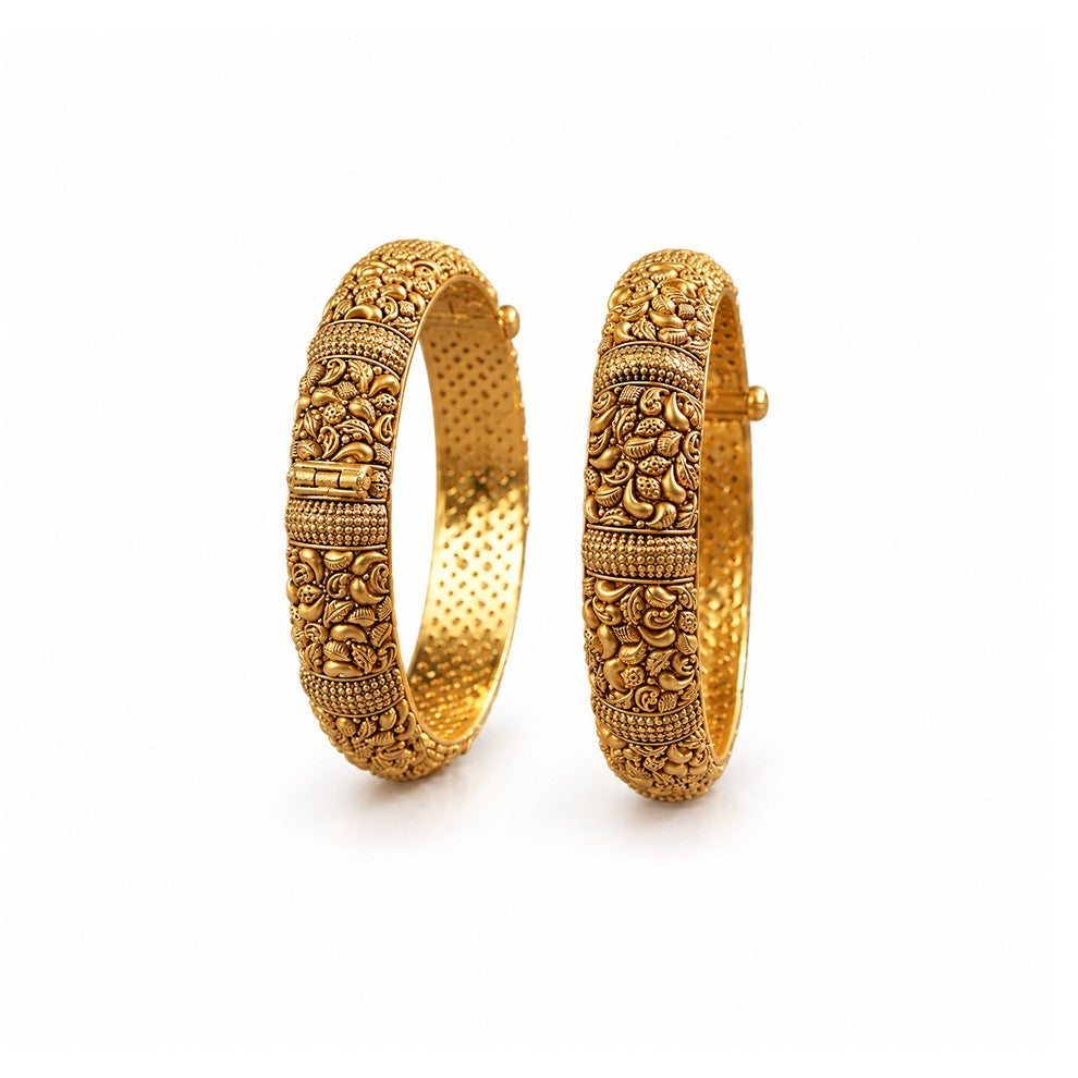 Pair of ornate gold bangles on a dark surface with decorative elements.