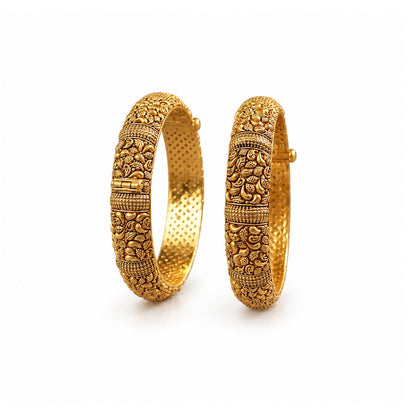Pair of ornate gold bangles on a dark surface with decorative elements.