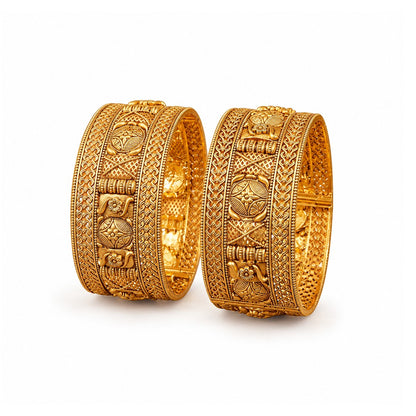 Two ornate gold bracelets on a red surface with a green decorative plate in the background.