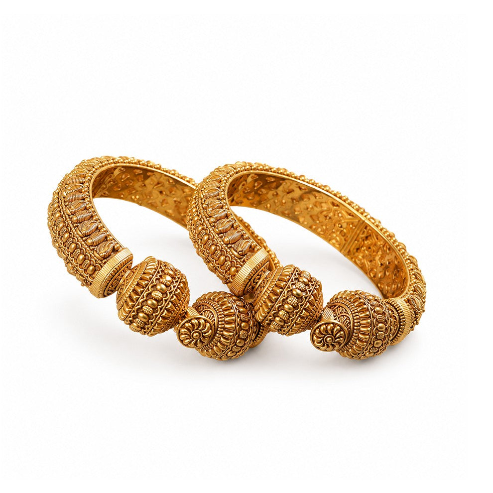 Pair of gold bangles on a dark wooden surface with a blurred background