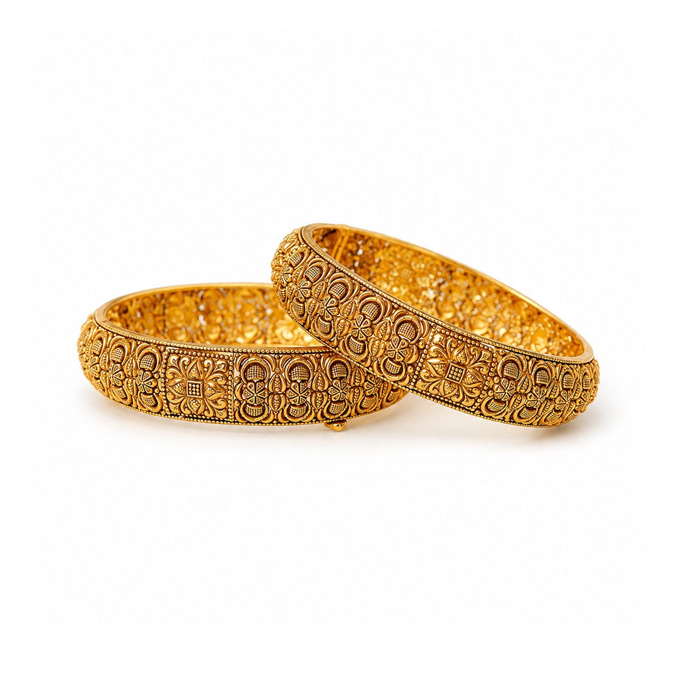 Two ornate gold bangles on a light surface with decorative elements.